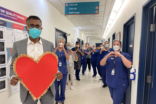 A/Prof Omar Farouque holding a red paper heart. In the background are other Austin Health staff making hearts with their hands.